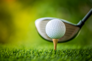 head of a golf club behind a ball sitting on a tee